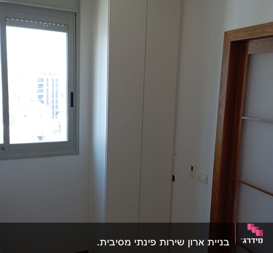 ארון עץ לבן בפינת חדר ליד חלון